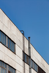 Exterior wall of an old industrial building against blue sky. Industrial site city area. Abandoned industry concept.