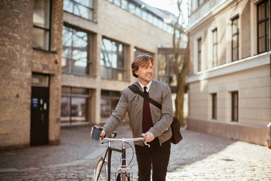 Caucasian middle aged man pushing his bicycle in the city while commuting to work