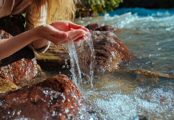 Young woman drinking water from a mountain spring