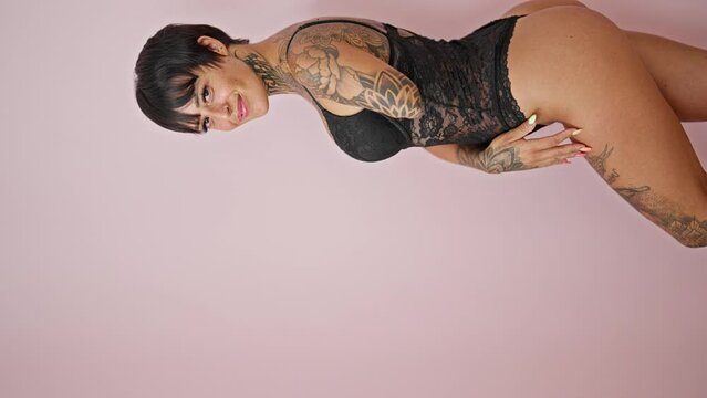 Hispanic woman with amputee arm wearing lingerie smiling over isolated pink background