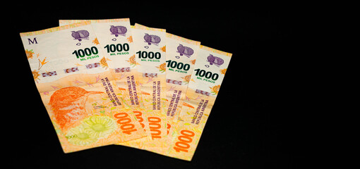 Banknotes of 1000 Argentine pesos, Argentine money, Argentine currency, Argentine pesos. Pile of several thousand Argentine peso bills, one thousand peso bills in cash on black background