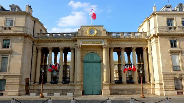 Back entrance of the French National Assembly (Palais Bourbon) with French flags fluttering in the wind