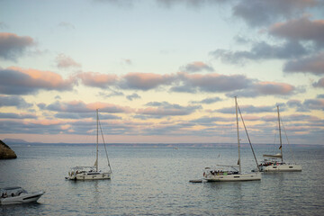 Experience the romance of Mallorca as boats moor in a coastal cove, kissed by the sun's last rays, showcasing the island's idyllic charm.