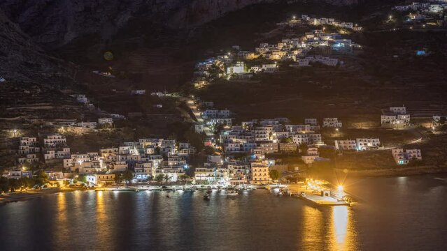Amorgos island aerial day to night transition timelapse from above after sunset. Traditional Greece - illuminated white houses on hills and turquoise sea, Cyclades