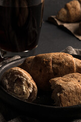 Traditional colombian food, Croissants and Handmade Corn and Flour Breads on a black plate served on a dark table, accompanied by hot black coffee.