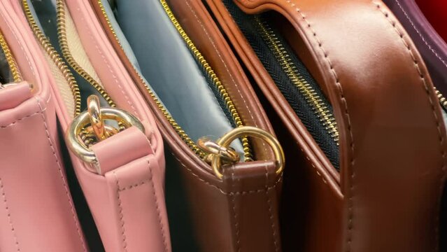 Women's leather zipper handbags in different colors in the accessories store window. Close up