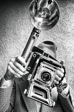 Classic 50s newspaper press photographer with press camera and large flash.