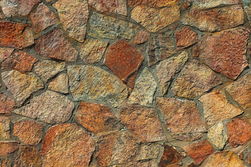 Multi-colored facade of the building wall is made of natural stone, a bit like granite and marble. Example of the decorative design