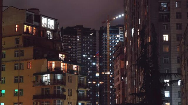 Multi-storey building with changing window lighting at night. Timelapse. Period of time of apartment buildings in Batumi. Crowded city with lights on and off at night 4K time lapse in urban metropolis