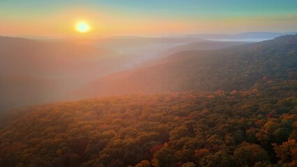Sunrise drone aerial over foggy autumn Arkansas ozark mountains with colorful fall forest trees