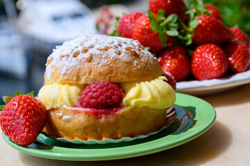 Tarte tropezienne or La Tarte de Saint-Tropez - dessert pastry consisting of filled brioche with cream and fresh berries served outdoor with fresh ripe strawberry