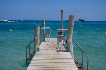 Naklejka premium Wooden pier and crystal clear blue water of legendary Pampelonne beach near Saint-Tropez, summer vacation on French Riviera, France