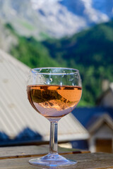 Drinking of dry dry rose wine from Savoy region with view on Hautes Alpes mountains with snow on tops in summer