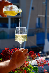 Pouring in glass of cold white Cote de Provence wine in yacht harbour of Port Grimaud, summer vacation on French Riviera in Provence, France