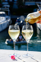 Pouring in glass of cold white Cote de Provence wine in yacht harbour of Port Grimaud, summer vacation on French Riviera in Provence, France