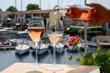 Pouring in glasses of cold rose Cote de Provence wine in yacht harbour of Port Grimaud, summer vacation on French Riviera Provence, France