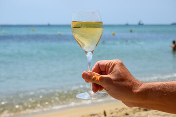 Summer time in Provence, glass of cold white wine on Pampelonne sandy beach near Saint-Tropez in Var department, France