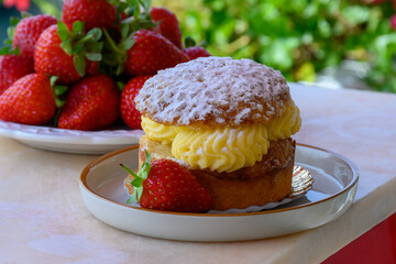 Tarte tropezienne or La Tarte de Saint-Tropez - dessert pastry consisting of filled brioche with cream and fresh berries served outdoor with fresh ripe strawberry
