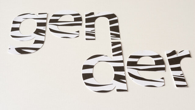 the word "gender" cut from white and black paper with pattern and arranged with the first three letters separated from the last three on blank paper