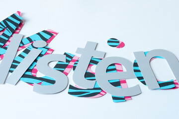 the word "listen" cut from gray paper and arranged on decorative letters (spells Music)