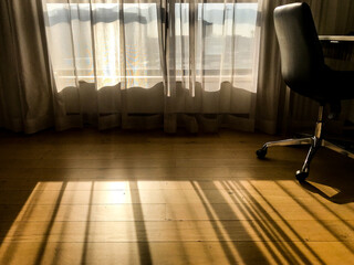 Sunlight coming in through window and curtains in Hotel room with shadows cast on floor