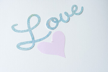 machine-cut paper sign with the word "love" and a pink heart on blank paper