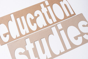 machine-cut stencil with the words "education" and "studies" cutouts on blank paper