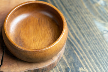 Wooden bowl on wooden table, empty round bowl for groceries and food