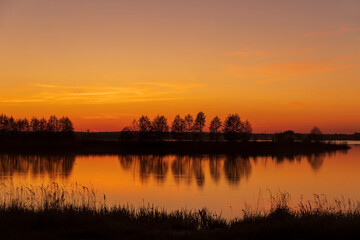 Fototapeta premium beautiful orange-yellow sunset on the lake in spring