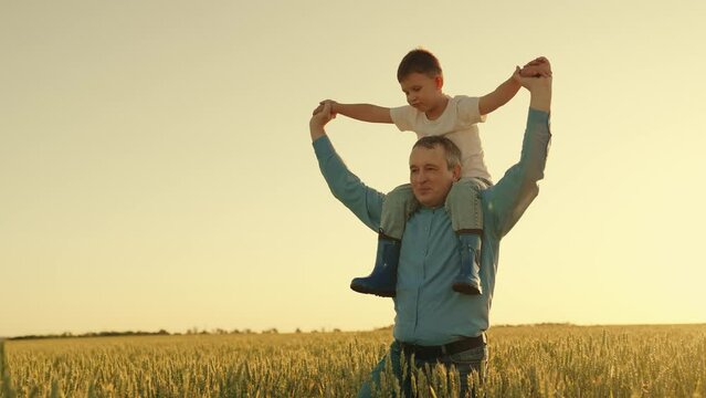 Agriculture. happy father farmer carries son child boy sunset. child sits happily his father shoulders wheat field. dad love child kid. beloved kid son arms his father. papa day. summer family walk
