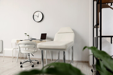 Modern medical office with doctor's workplace and examination table in clinic