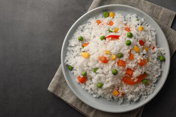 Delicious rice with vegetables on grey table, top view. Space for text