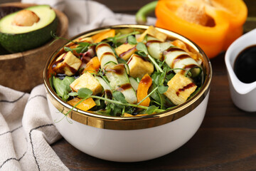 Delicious salad with tofu, vegetables and balsamic vinegar on wooden table, closeup