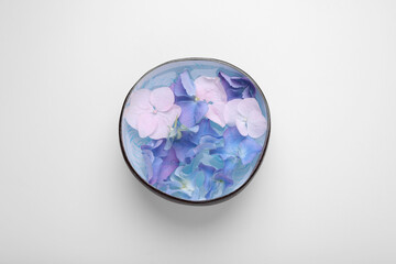 Spa composition. Aromatic water and flowers in bowl on white background, top view