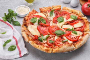 Delicious Caprese pizza and ingredients on grey table