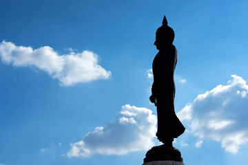 Silhouette of large Buddha statue and blue sky with clouds