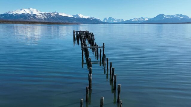 Wood Pier At Puerto Natales In Ultima Esperanza Chile. Snowy Mountains. Bay Water Landscape. Ultima Esperanza Chile. River Background. Wood Pier At Puerto Natales In Ultima Esperanza Chile.
