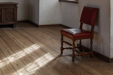 Interior view, moody tone single wooden leather vintage chairs lay beside white wall inside vintage...