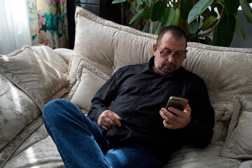 man sitting on sofa and looking at smartphone