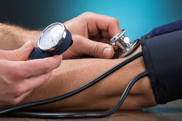 Doctor Checking Blood Pressure Of Patient At Table