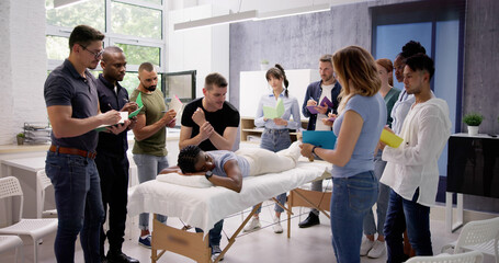 Male Instructor Teaching Massage Technique To Group
