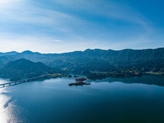 Obraz premium Aerial photography of a large reservoir with blue sky and white clouds and mountains
