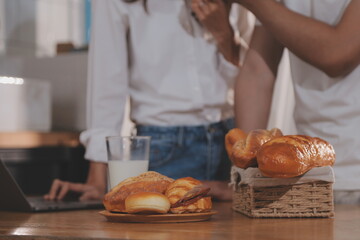 Handsome man sitting near his wife at kitchen. Family couple see social media, surf the web while sitting at kitchen table with generic laptop. Couple working with laptop at home