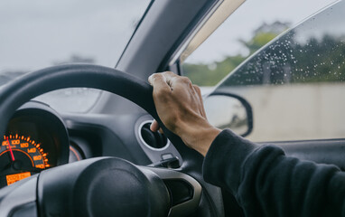 Side view of male driver holding steering wheel while driving car.