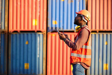 African factory worker or engineer using tablet computer and checking work in containers warehouse...