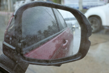 water droplet on side mirror of red car on rainy day