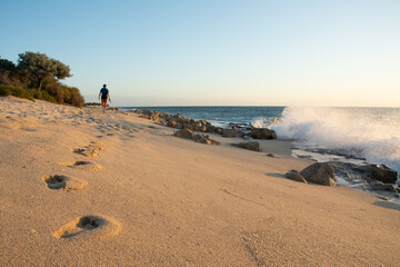 A man walking on sandy beach during the sunset leaving footprints. Anakao Beach, Madagascar. 