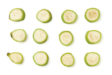 Slice unripe bananas (green) set in row isolated on white background, unripe bananas are versatile and high in fiber. Top view of sliced banana inside, seeds and green banana peel.
