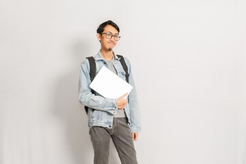 A male with his folded laptop standing isolated in front of white background. Indonesian or southeast asian model.