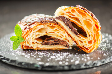 Freshly baked croissant filled with dark chocolate, topped with chocolate flavoured fondant and...